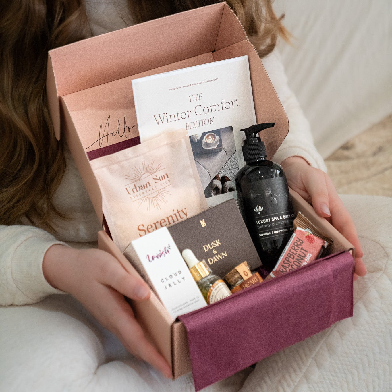 Woman holding a box of skincare products on a white couch